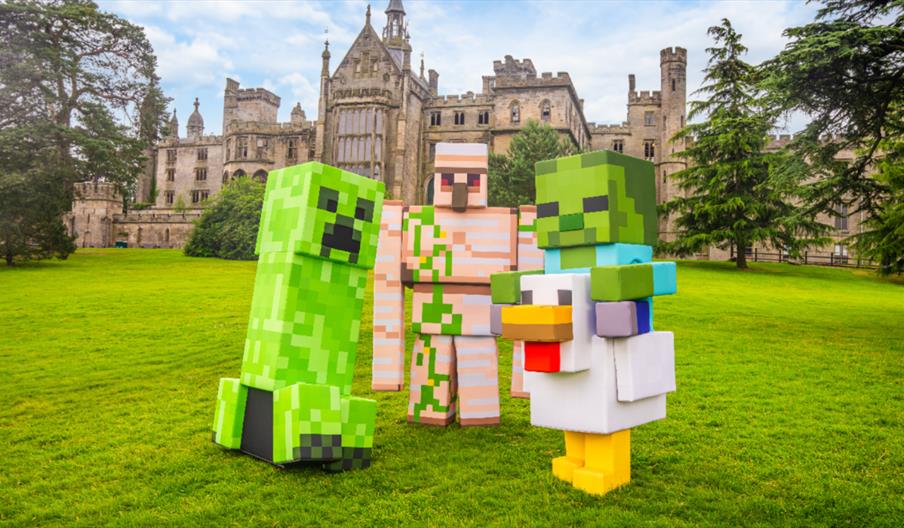 Large Minecraft character models displayed on the lawn of a historic estate.