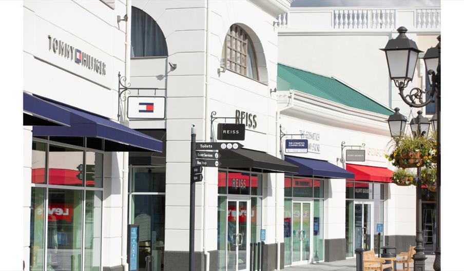 Outdoor shopping street with branded store fronts.
