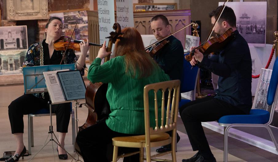 Chamber musicians performing a string concert inside a museum gallery.