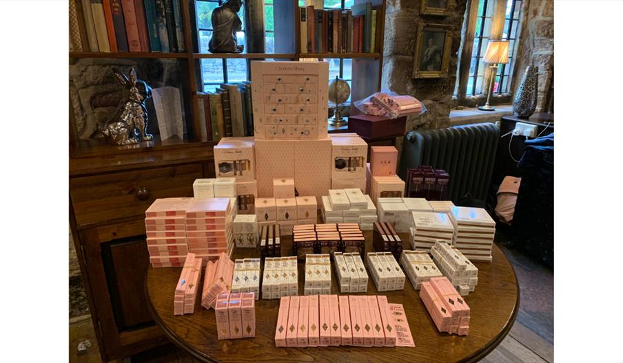 Charlotte Tilbury beauty products neatly displayed on a round wooden table, including boxed makeup and skincare items arranged in rows inside a histor