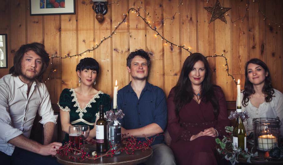 Image shows the five band members in a pub