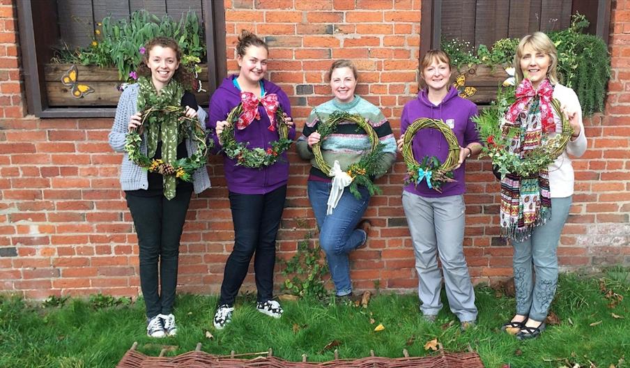 people holding Christmas wreath