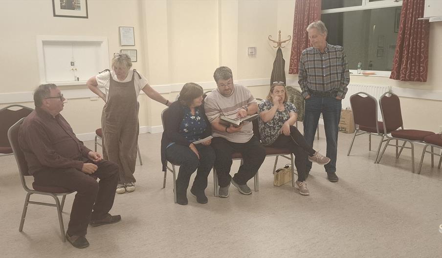 Six actors perform in a village hall