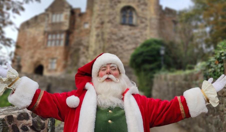 Image shows Santa with his arms spread out, in front of Tamworth Castle