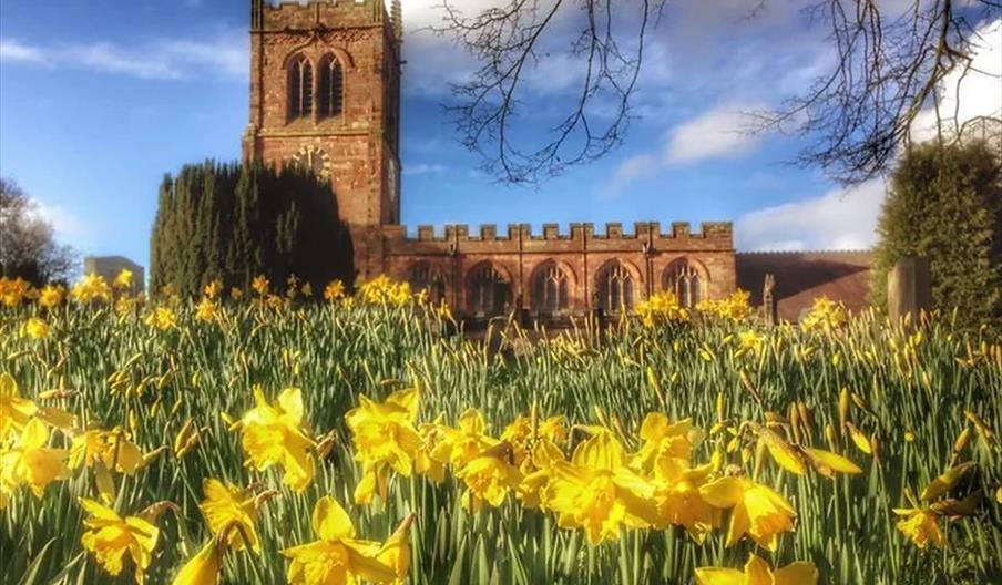 A picture of a church on a sunny day, with daffodils blooming in front of it