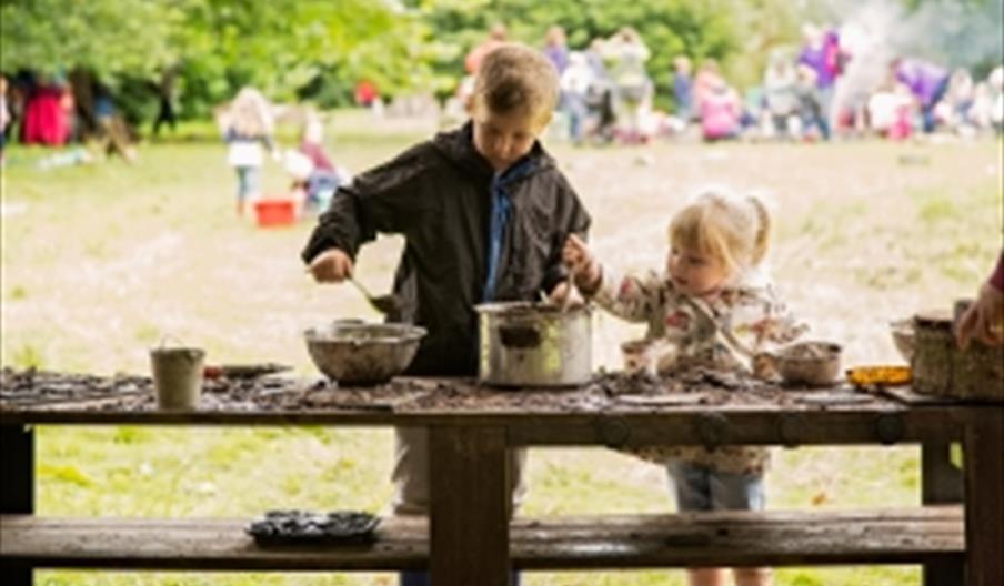 Two young children get their hands dirty in a mud kitchen at The Wolseley Centre, Staffordshire