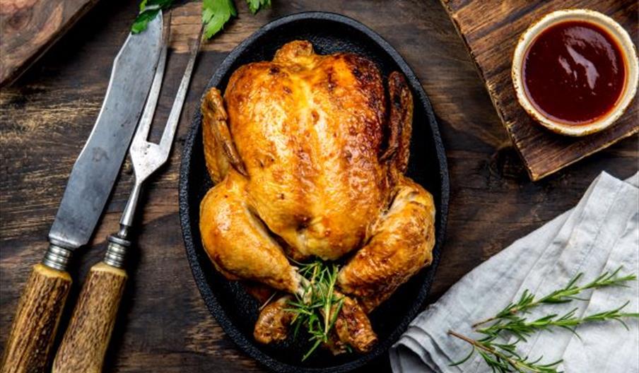 Image shows a roasted chicken, ready to be carved