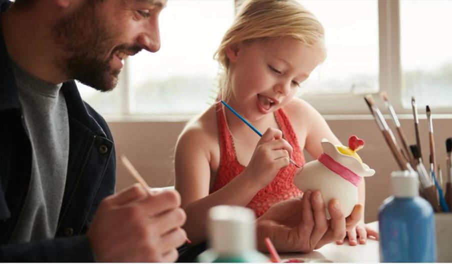 Man and child painting pottery.