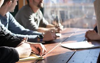 People sitting a table talking and taking notes