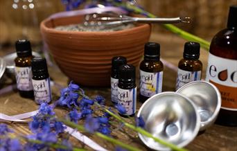 An aromatherapy kit, with bottles, lavender, bowls, and other tools including a whisk, on a table