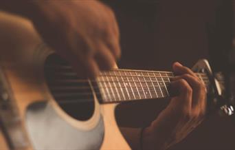 Person playing acoustic guitar with a capo