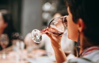 A person drinking from a clear wine glass