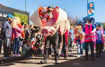 The annual Pig Walk in Stoke-on-Trent, featuring two people walking along in a huge pig costume, as others walk behind, and visitors gather to watch