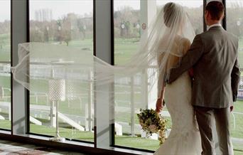 A couple, on their big day, gaze out over the racecourse
