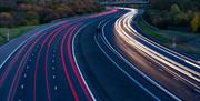 An image taken at night on the M6 Toll Road, Staffordshire, showing the colourful traces of vehicle lights in both directions