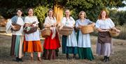 Six ladies holding wicker baskets and smiling to the camera