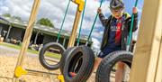 A boy plays on some rubber tyre swings in a play area
