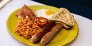 Sausages, beans, tomato, fried egg and a Staffordshire oatcake on a plate