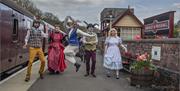 Performers from an Alice in Wonderland experience on the platform, with Alice, the Mad Hatter and other characters on view