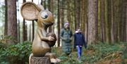 Image shows a sculpture of the Mouse from The Gruffalo, sitting on a tree stump with a nut