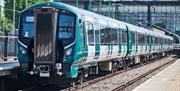 A new train, with London North Western livery, beside the platform in a station, on a sunny day.