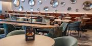 A view of the dining area at Ibis Styles, Burton upon Trent, with a long table and a selection of smaller ones