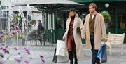 A couple with their shopping bags walk hand-in-hand