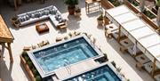 An image from above, showing the spa terrace at Hoar Cross Hall on a sunny day, with two inviting looking pools, a luxurious corner sofa, and seven be