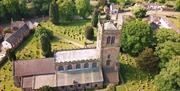 A drone shot of a church, with the graves and trees dotted around it