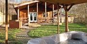 A hot tub on the porch of one lodge, looking over at another cabin, on a sunny day
