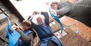 Two boys with their grandad, all wearing chainmail and pointing their swords at the camera
