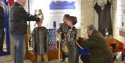 Some younger visitors try on Anglo-Saxon armour with their parents helping them