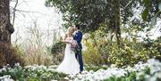 Image shows a bride and groom, posing for wedding photos in the woodland next to The Moat House