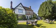 Image shows a glorious day at The Moat House, with the sun beating down on the farmhouse, tables and greenery