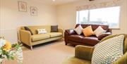 The lounge area with big sofas and armchairs at Tolldish Cottage