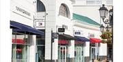 Outdoor shopping street with branded store fronts.