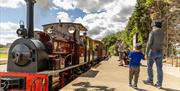 A father and son about to board a heritage steam train on a sunny day
