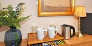 Tea and coffee making facilities, alongside the kettle, a lamp, and a vase with flowers, in Room 3 at The Fountain Inn