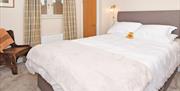 Bedroom image showing large comfortable double bed, with a teddy between the pillows