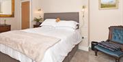Image shows bed, chair, and other furnishings in one of the bedrooms