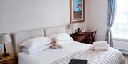 Bedroom with double bed, bedside tables, towels on the bed, and a teddy sitting between the pillows