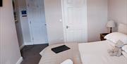 Image shows the entrance to one of the bedrooms, with a view of the bed, and a leather folder, teddy and towels on it