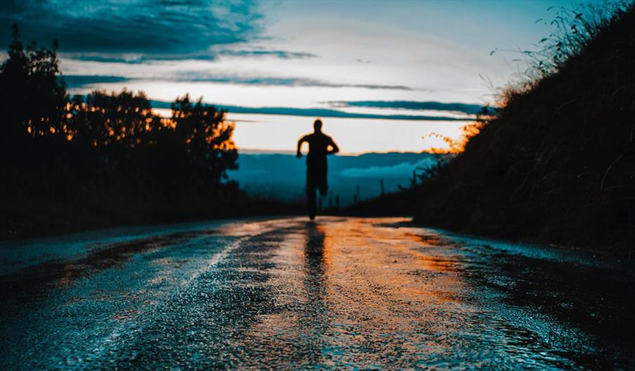 Runner on a wet road at sunset Runner on a wet road at sunset