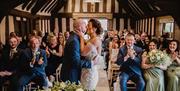 Image shows a couple kissing at the end of their ceremony, clapped by their guests, in the beautiful suite